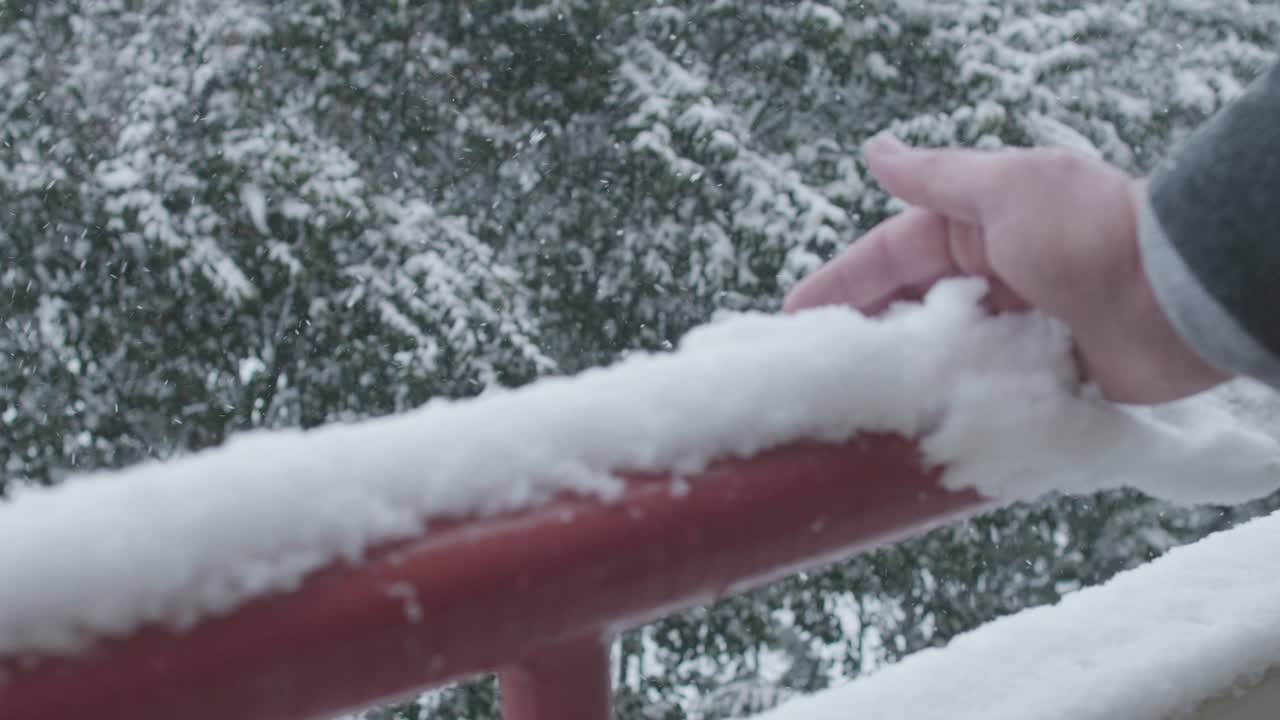남자가 발코니 레일링에서 눈을 고 있다
