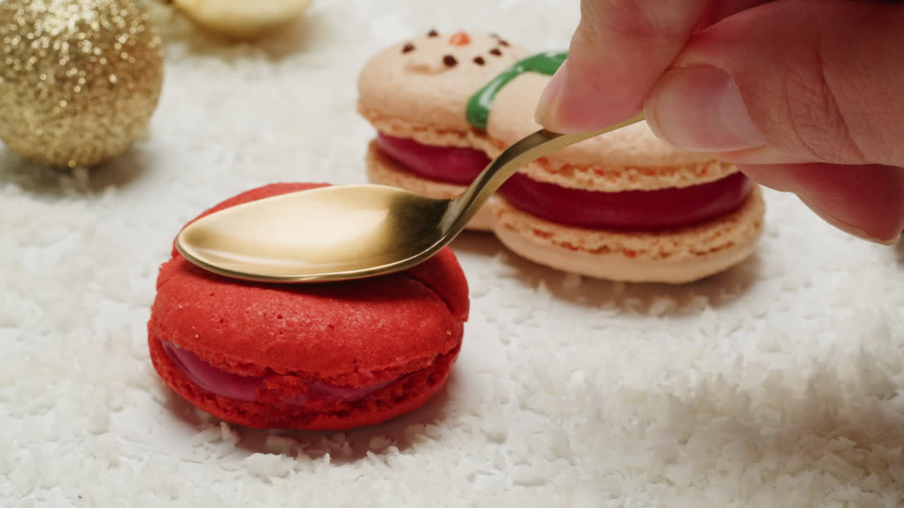Hand holding gold spoon over christmas macarons