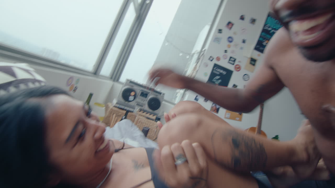 Young Couple Laughing, Playing and Tickling on Bed