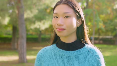 portrait of a happy young asian woman smiling in a park