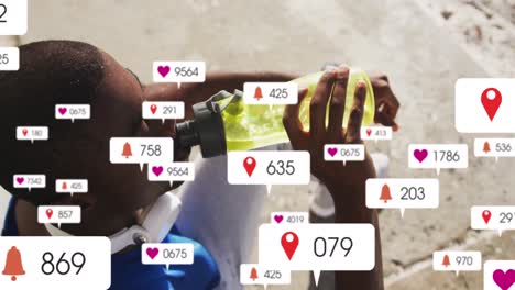 Animation-of-notification-icons-with-changing-numbers-over-african-american-man-drinking-water