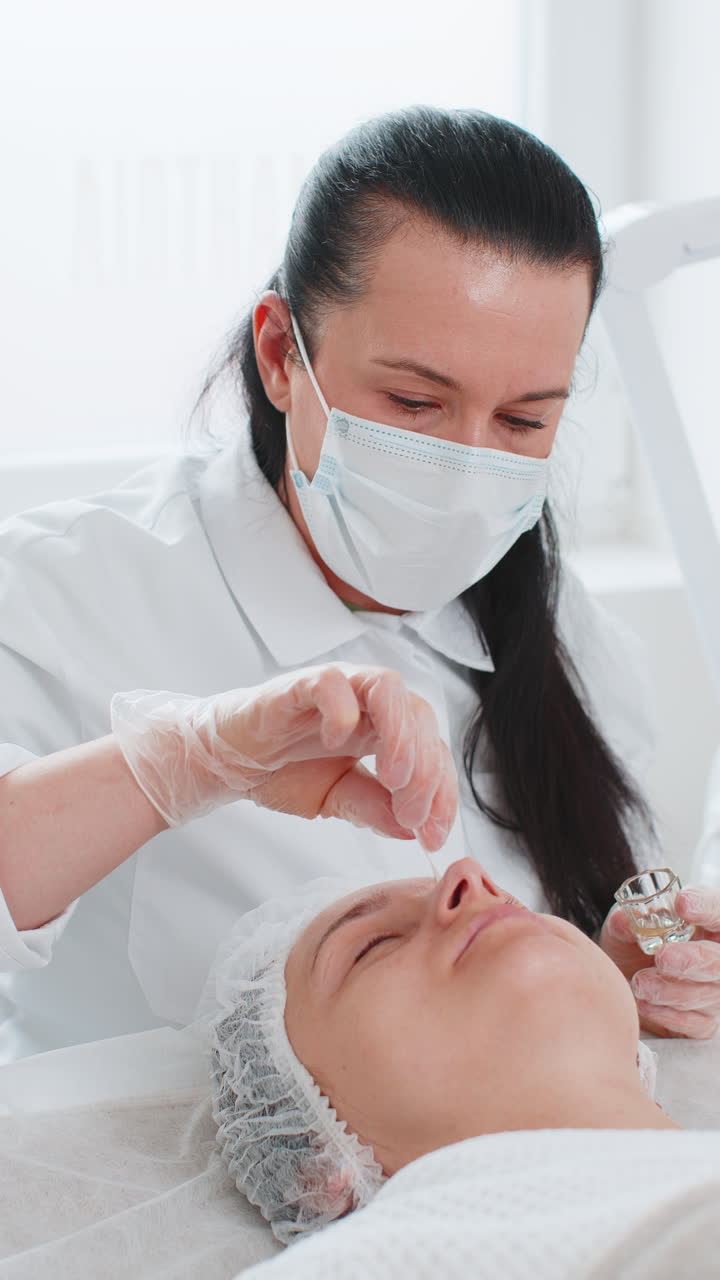 미용사는 여성의 눈 주변 피부에 보습성 질 산을 적용합니다. 노화 방지 치료