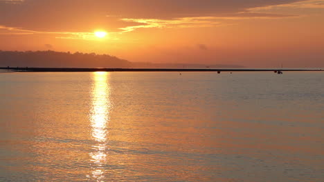 Statische-Sonnenaufgangsaufnahmen-über-Ruhigem-Meer-Mit-Gelbem-Und-Orangefarbenem-Himmel