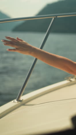 cheerful female stretches arms to sides looking out of hatch of yacht cabin. simulate flight and enjoy boat ride on vacation. water trip in summer