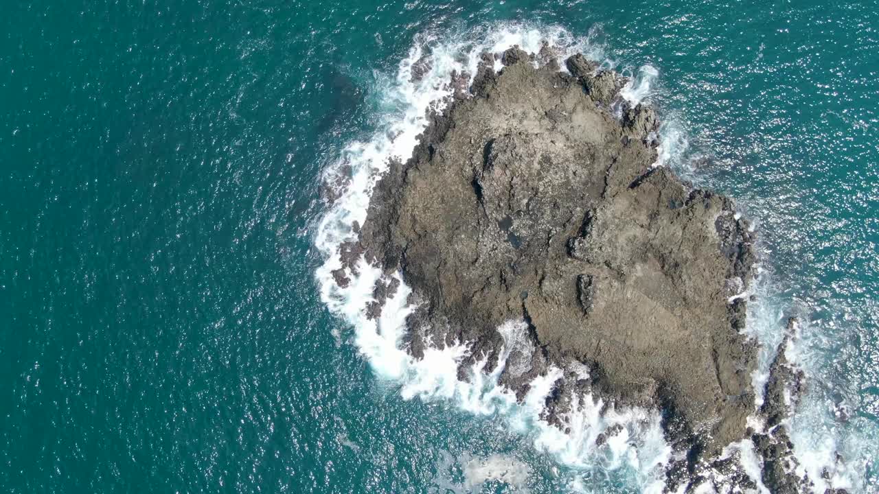 aéreo de arriba hacia abajo sobre las olas del mar rompiendo en las rocas cerca de la costa de kebumen, java central en indonesia