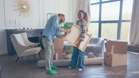 diverse family have moved into apartment and discussing where to hang painting