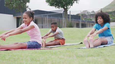 Video-of-diverse-schoolgirls-and-schoolboy-practicing-yoga-stretching-in-outdoor-class,-copy-space