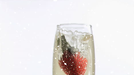 animation of strawberry falling into glass of champagne, with confetti falling on white background