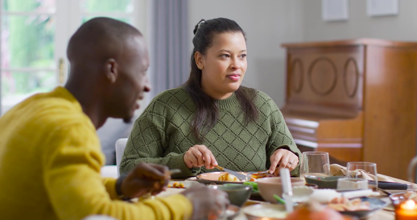African American couple starting meal home dining table, woman cutting knife and fork, man eating