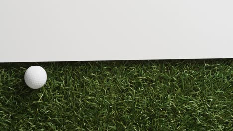 close up of golf ball on grass with white background, copy space, slow motion