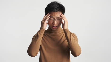 asian man showing headache in front of the camera.