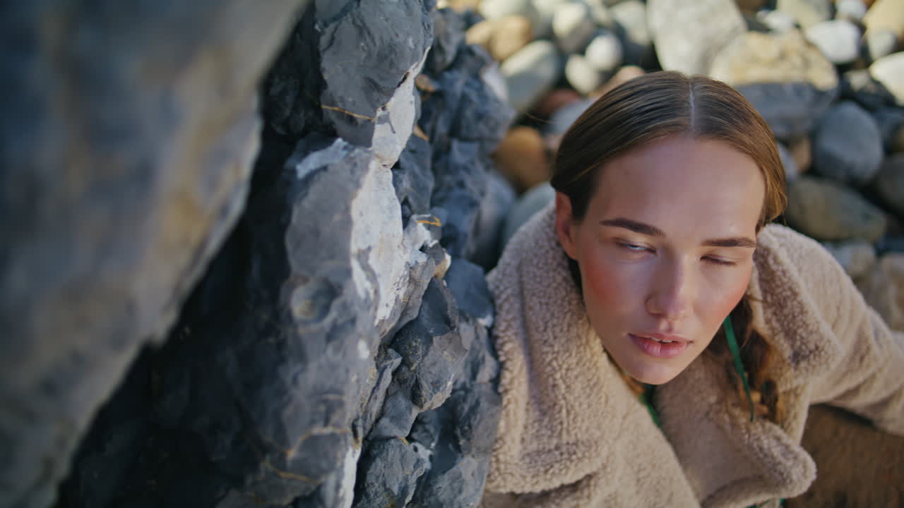 바가에서 휴식을 취하는 패션 소녀가 돌을 가까이에서 포즈를 취하고 있습니다.