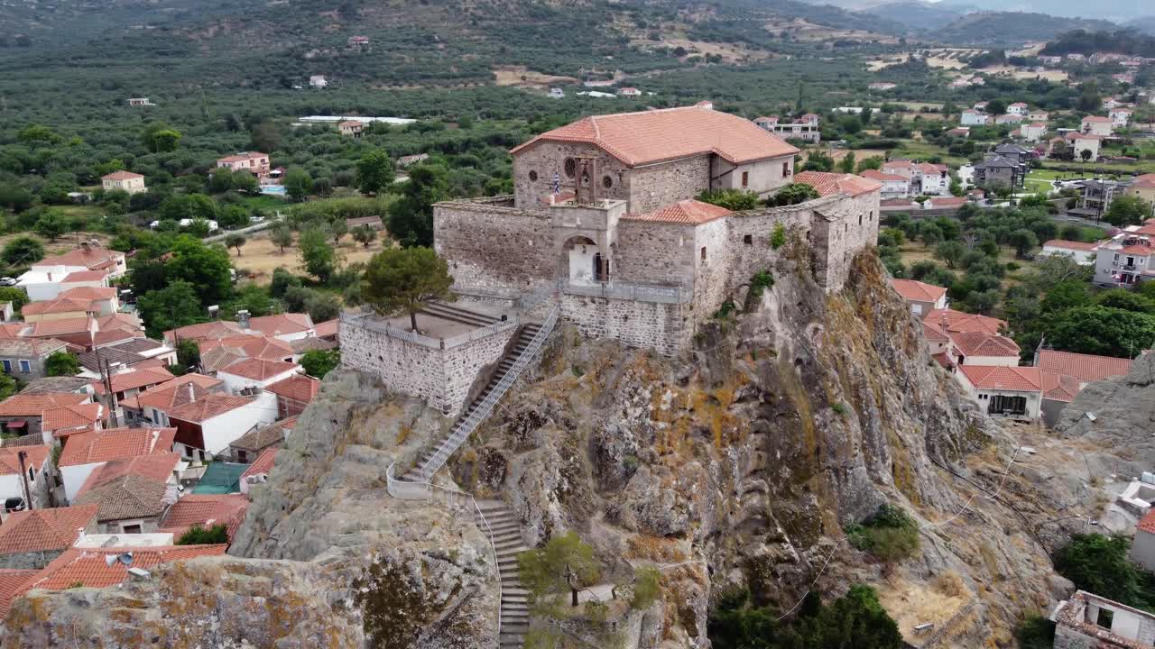 Virgin Mary Greek orthodox church at top of rock surrounding old Petra village, Aegean sea and olive groves garden, Lesbos, Aerial closeup