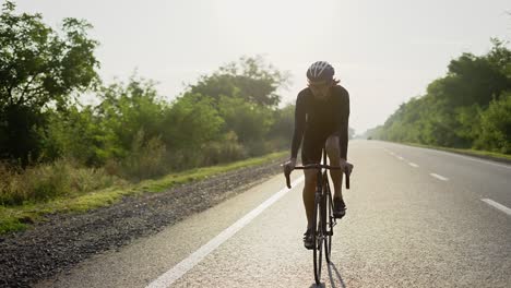 Male-cyclist-in-helmet-rides-bicycle-along-an-empty-track,-front-view