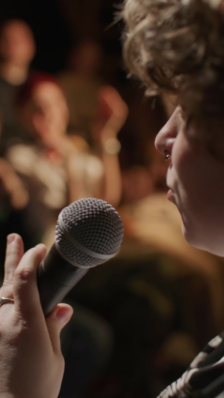 Giovane comica che esegue un monologo durante una serata open mic in un comedy club
