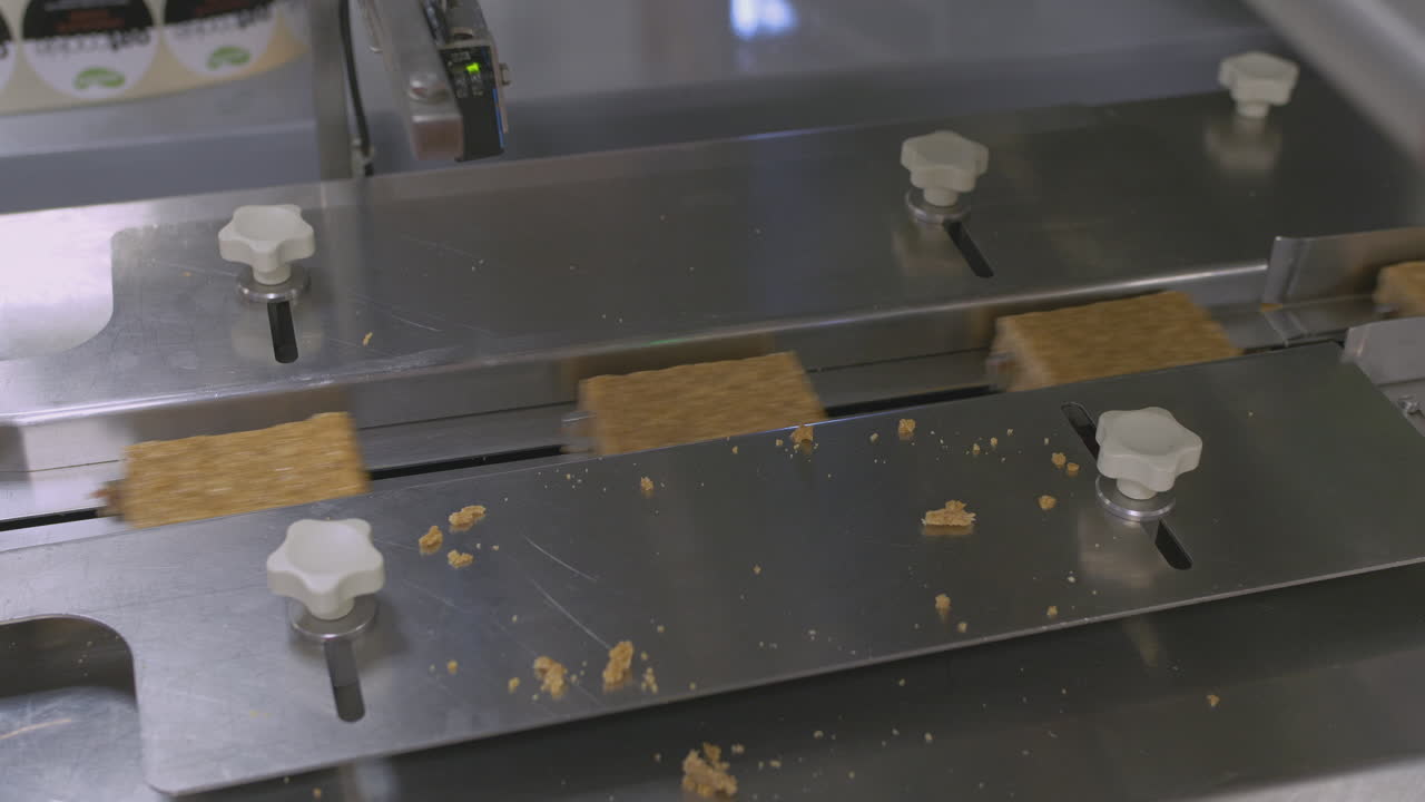 las barras de pastel en una fábrica se mueven a lo largo de un transportador a medida que se mide el ancho de cada barra.