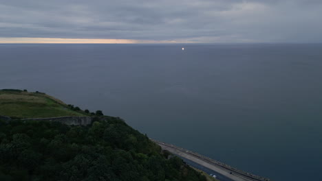 establishing drone shot looking out to sea from scarborough at night with boat light in ocean