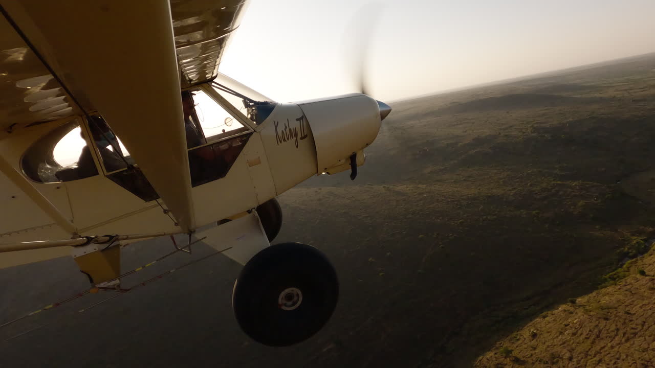 Avião em sobrevoo de um vale com rio, projetando sombra.