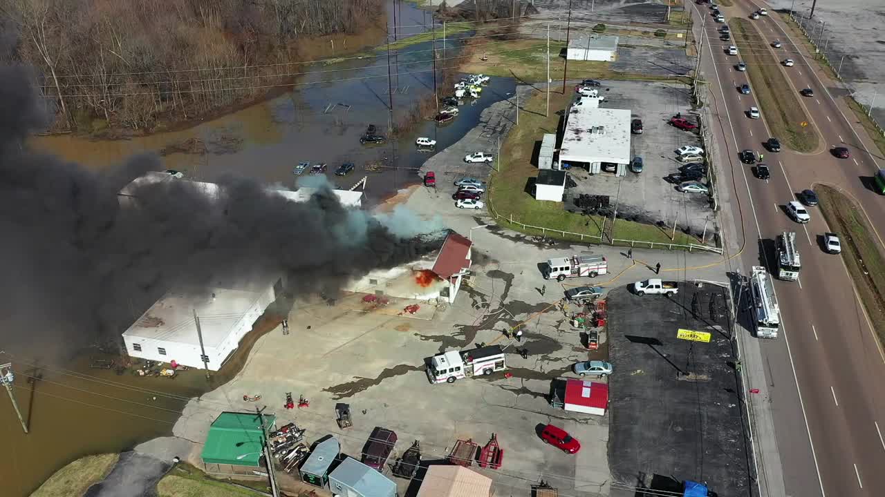 Ascending drone view of an active fire with multiple agencies in attendance including local fire and police