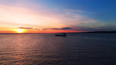 amid the golden hour's glow, an aerial drone reveals a peaceful barge sailing beneath humber bridge as the sun sets