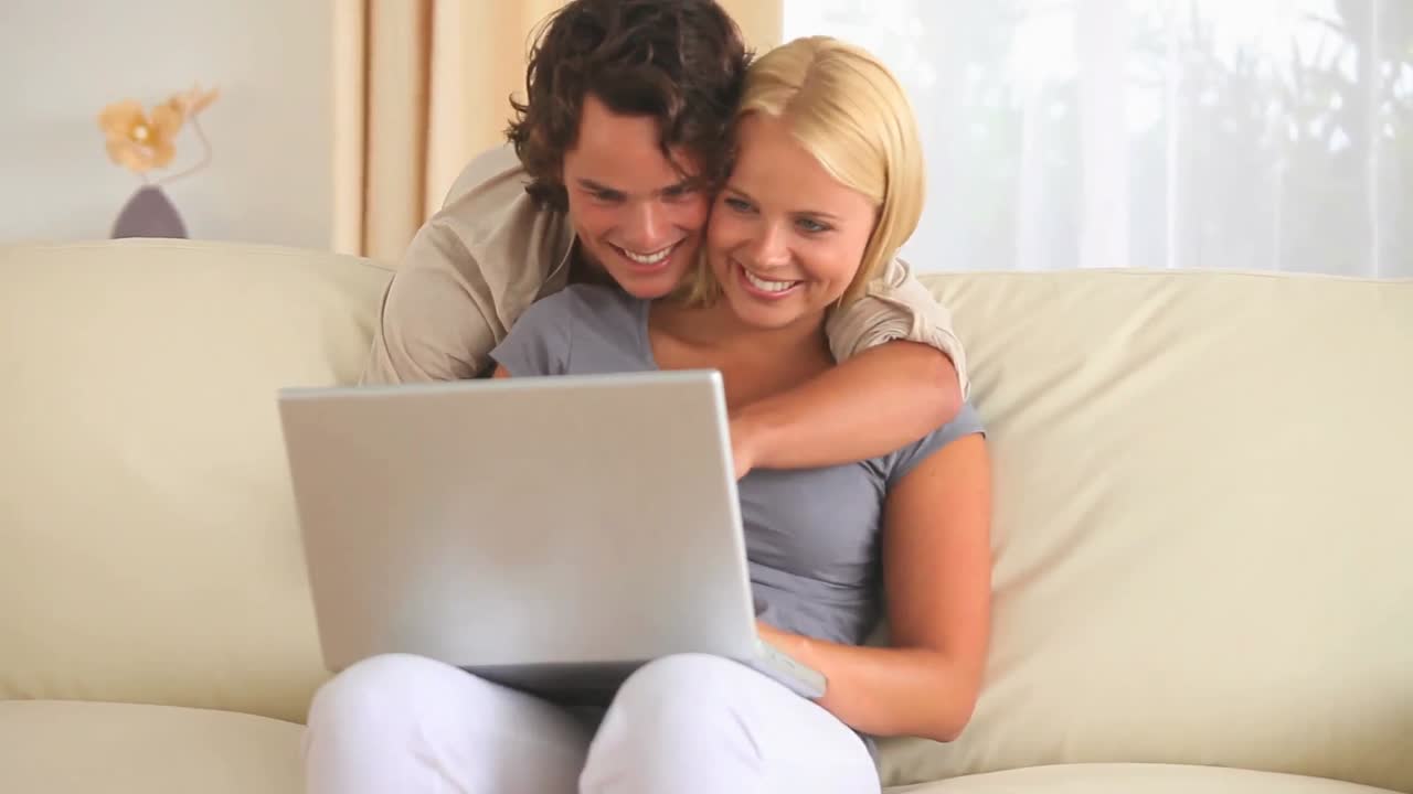 pareja abrazada mirando una computadora portátil