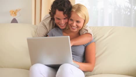 hugging couple looking at a laptop