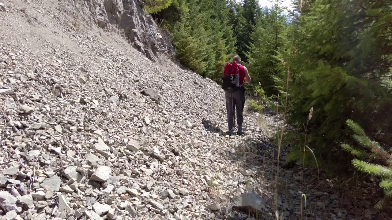 excursionista masculino sube el talus rocoso y el esquisto en la ladera de una montaña - thunder mountain, vancouver island, bc, canadá