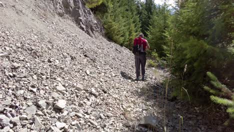 male hiker walk up rocky talus and shale on the side of a mountain - thunder mountain, vancouver island, bc, canada