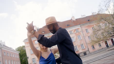 pareja interracial bailando salsa en una plaza pública