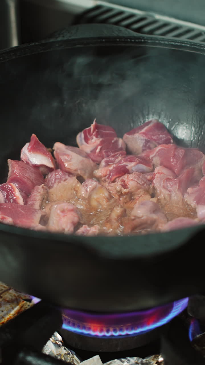 Daging Mentah Mendesis dan Digoreng dalam Panci Besar di Atas Api Gas