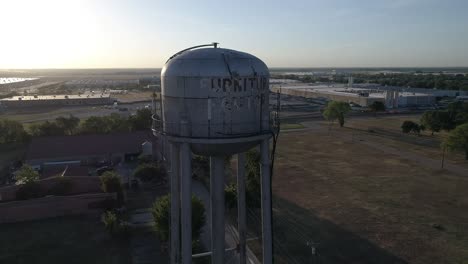 Torre-De-Agua-En-Mckinney,-Texas,-Cerca-De-La-Antigua-Fábrica-De-Algodón-Que-Lee-La-Fábrica-De-Muebles-Durante-El-Amanecer