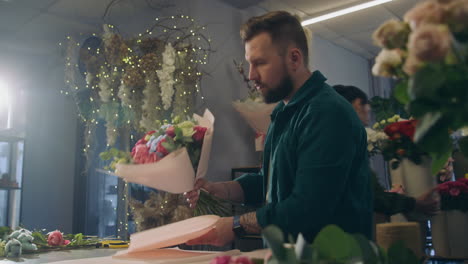florista masculino concentrado envuelve ramos de flores