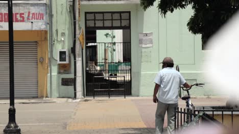 short hispanic male walking in a town in mexico with a bicycle