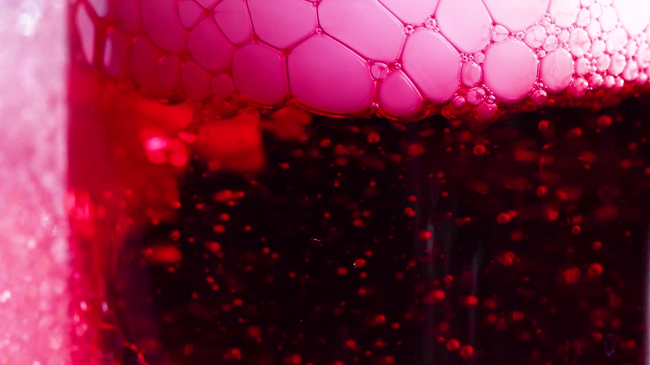 un líquido rojo vibrante con hielo seco crea efectos de burbujas, mostrando un experimento científico dinámico con colores y texturas vívidas