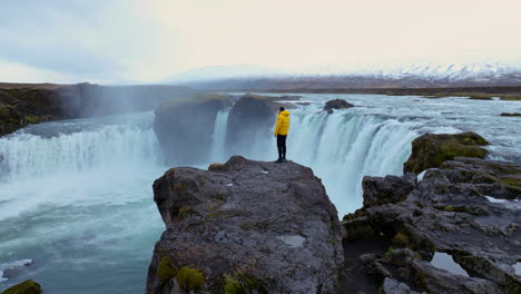 man on the cliff next to godafoss waterfall in iceland - drone shot