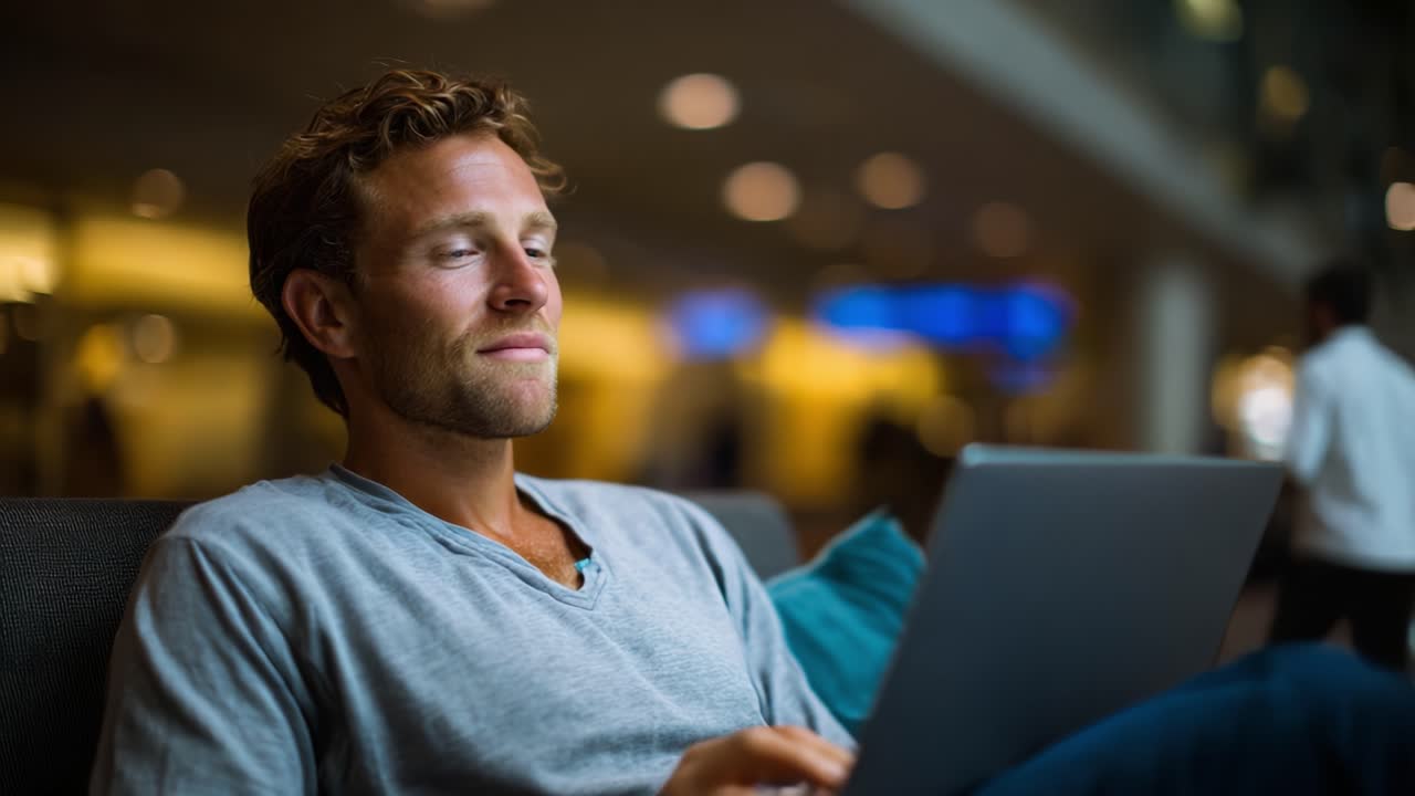 Un uomo concentrato lavora al laptop in un ambiente interno moderno, mostrando concentrazione e produttività in un’atmosfera rilassata con illuminazione soffusa.