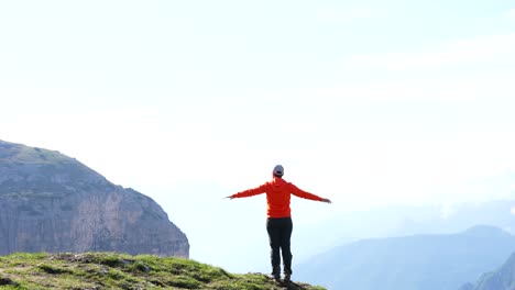 Caucasian-man-in-orange-jacket-raising-hands-in-Auronzo-Valley