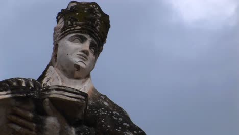 un lapso de tiempo en la nube moviéndose sobre una estatua de una mujer sosteniendo un libro