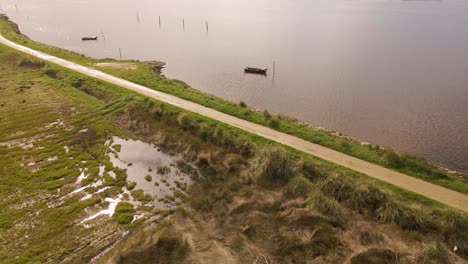 Vista-Aérea-De-4k-De-La-Silueta-De-Dos-Viejos-Barcos-De-Pesca-Anclados-En-Medio-De-La-Ría-De-Aveiro,-Estuario-Del-Río-Vouga,-Drone-Girando-A-La-Izquierda,-60fps