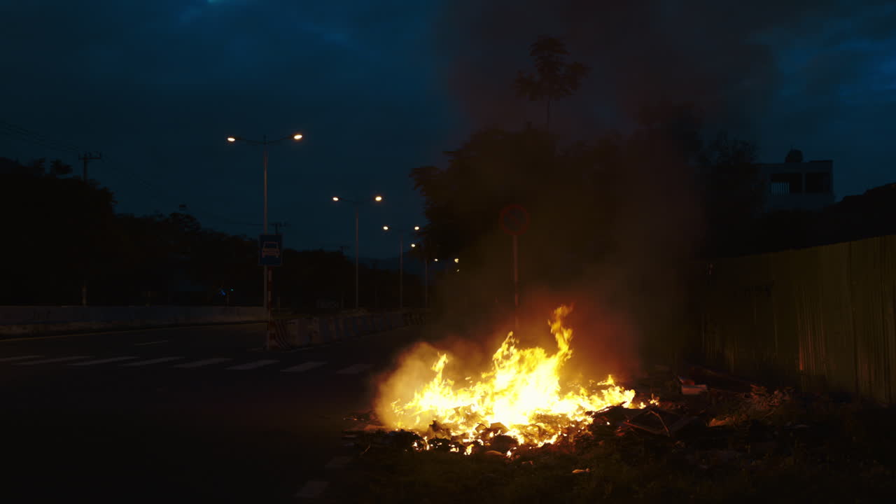 Bonfire Burning on the Side of a Road at Night