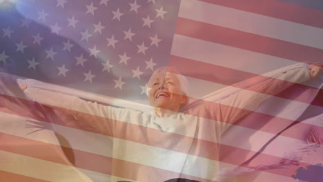 animation of flag of united states of america over senior woman having fun