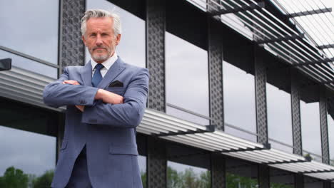 portrait of serious senior businessman ceo chairman standing outside modern office building