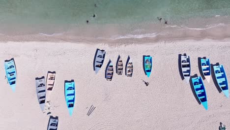 overhead view of boats on the shore of quemaito beach with tourists swimming in the clear water