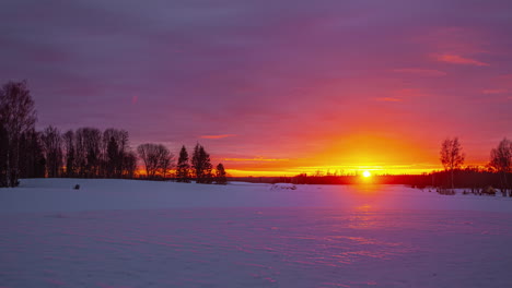 Snowy-landscape-timelapse-with-the-orange-sun-on-the-horizon-hiding-at-sunset-and-the-clouds-advancing-in-the-sky