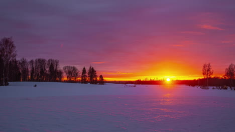 snowy landscape timelapse with the orange sun on the horizon hiding at sunset and the clouds advancing in the sky