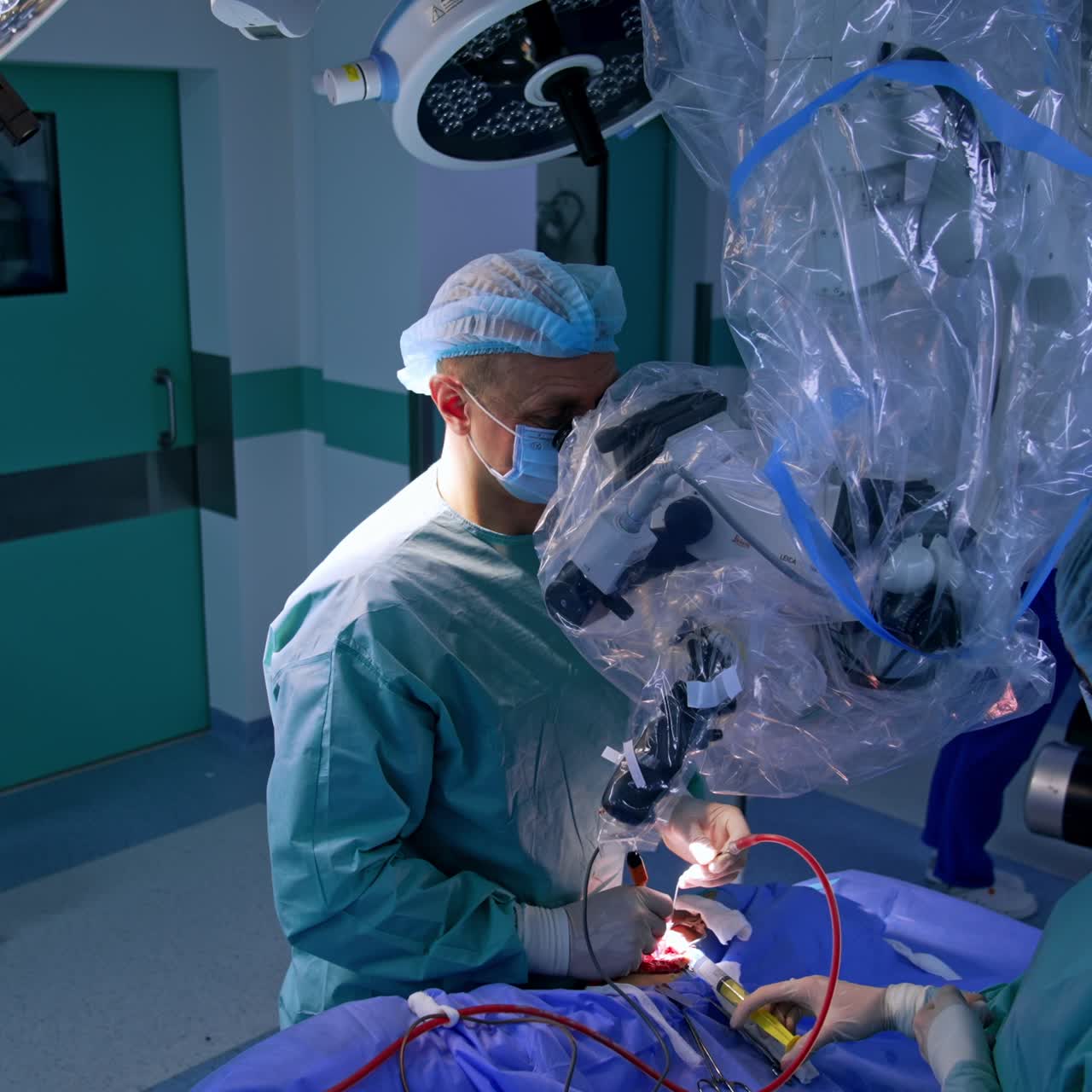 Attentive male surgeon looking at microscope performs surgery. Doctor applies devices holding them in both hands. Nurse uses syringe. Top view
