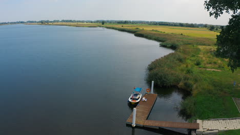 aerial view of small pier near the river with fields in the background