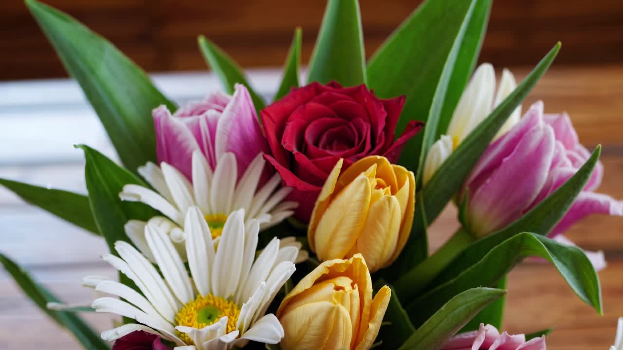 Video ravvicinato di un vivace bouquet di fiori con margherite, tulipani e una rosa