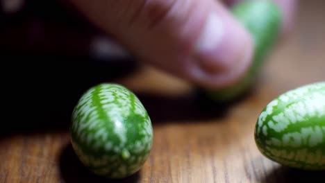Raw-fresh-tiny-green-Mexican-cucamelon-picked-from-wooden-kitchen-surface-dolly-right-selective-focus