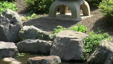 Tilt-down-from-Japanese-stone-lantern-to-its-reflection-in-pond